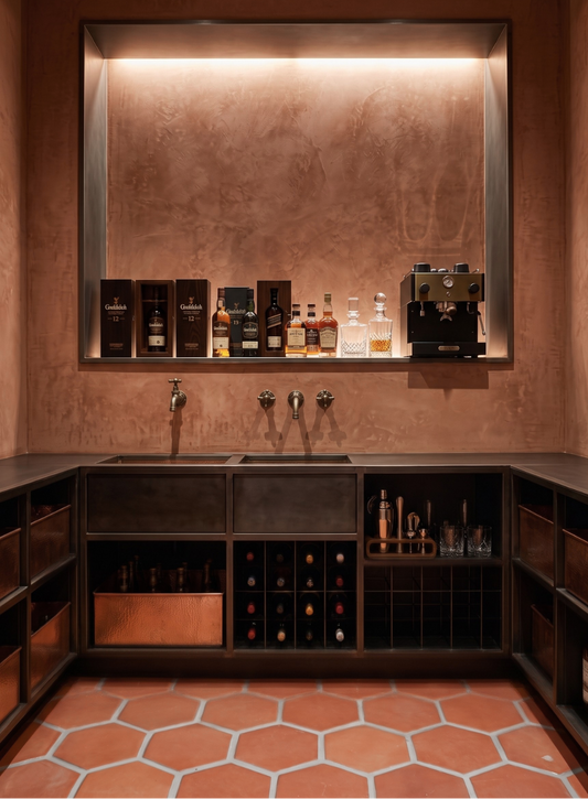 A luxury home bar setup featuring a copper-toned textured backlit wall, dark wood L-shaped cabinetry with integrated wine racks, a double sink with three chrome faucets, and a built-in shelf displaying various premium liquor bottles and bar equipment.