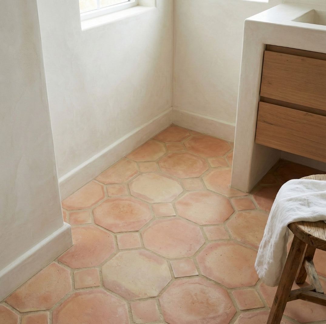 Peach terracotta Octagon + Square tiles from Clay Imports covering a floor in a light-colored room with a vanity and stool.