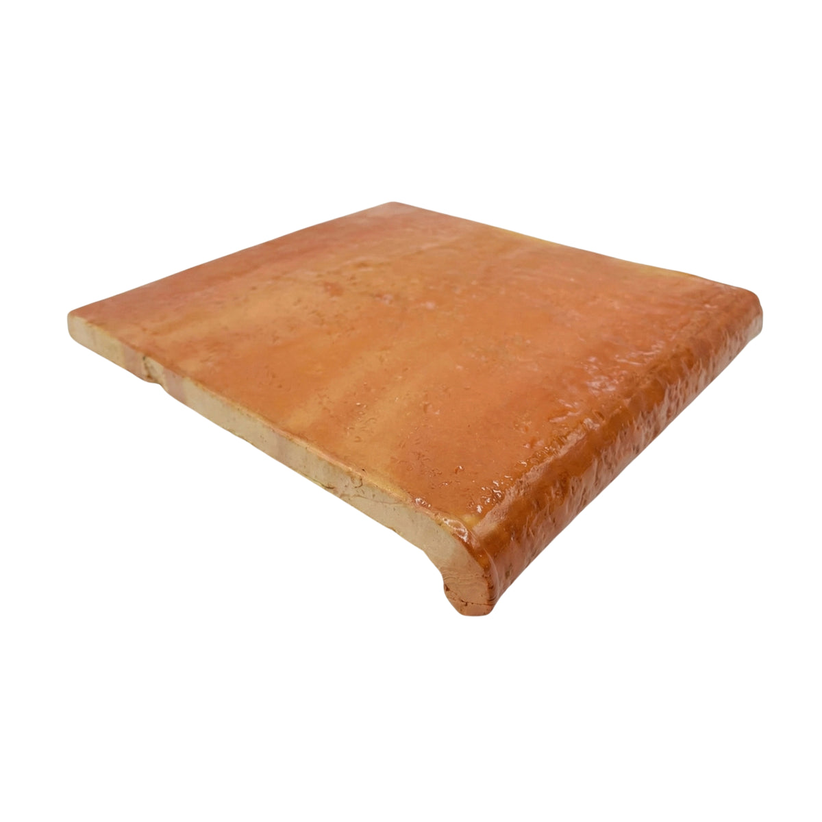 Antique gloss terracotta coping tile by Clay Imports with a rounded edge and shiny, rustic surface, viewed at an angle.