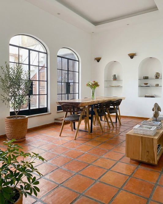 Organic 12x12 terracotta floor tiles by Clay Imports, covering a dining room floor with wide gray grout lines.