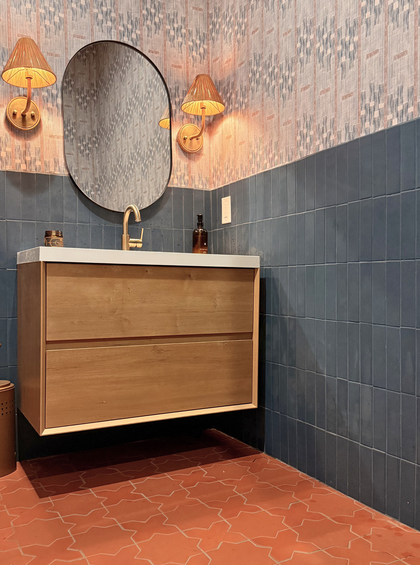 Dark blue 2x8 rectangular clay tiles by Clay Imports on a bathroom wall, styled with patterned wallpaper and terracotta floor tiles.