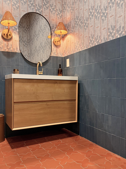 Dark blue 2x8 rectangular clay tiles by Clay Imports on a bathroom wall, styled with patterned wallpaper and terracotta floor tiles.