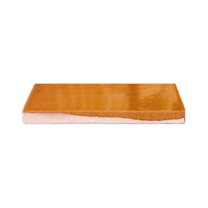 Terra Crackle Gloss sample by Clay Imports, a rectangular piece with a textured, glossy brown top and lighter base.