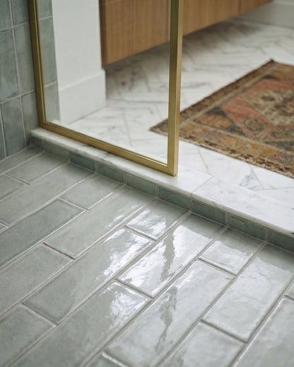 Horizon Arctic Gloss 2x6 tiles by Clay Imports, glossy light green, laid in an offset pattern on a shower floor.