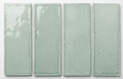 Four rectangular 2x6 light seafoam green glossy tiles by Clay Imports, showing subtle texture variations.