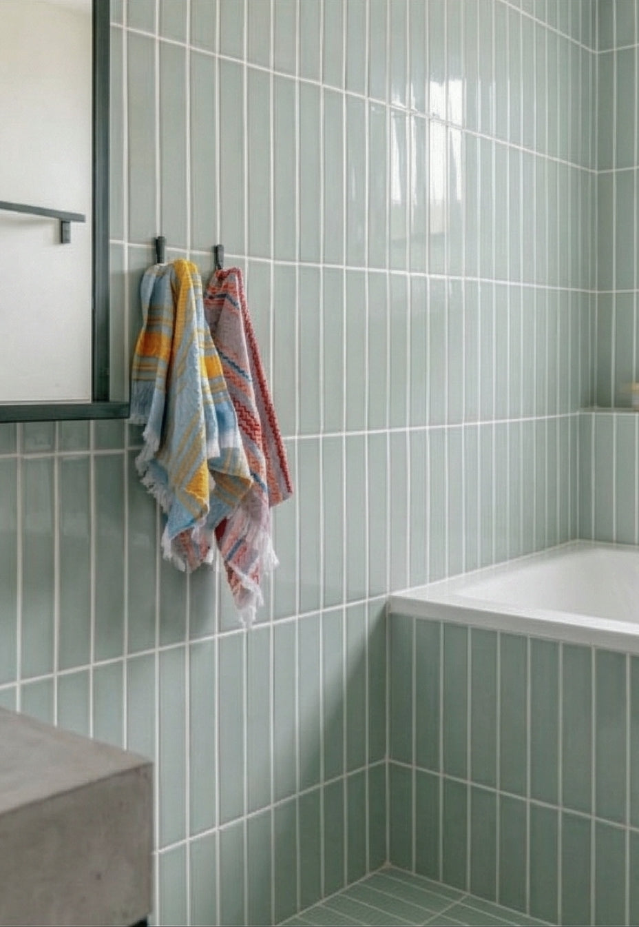 Light sage green glossy solid tile by Clay Imports, vertically laid with white grout in a modern bathroom.