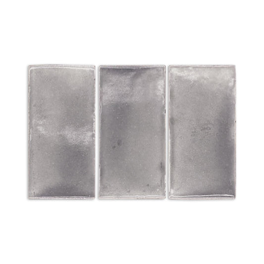 Three graphite gloss tile samples by Clay Imports, rectangular and silver-gray with a subtle textured finish.