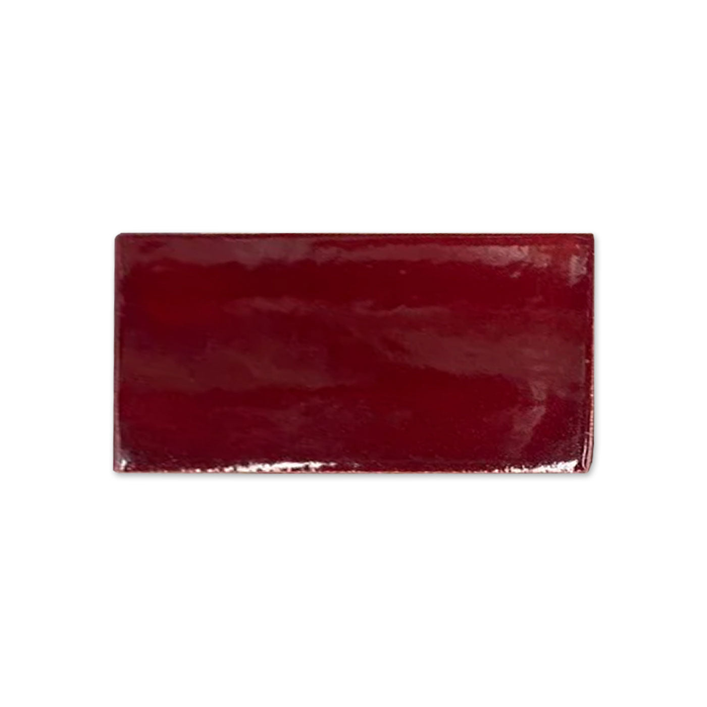 Oxblood red glossy tile sample from Clay Imports, rectangular with a rich, reflective finish and slightly textured edges.