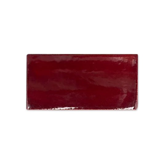 Oxblood red glossy tile sample from Clay Imports, rectangular with a rich, reflective finish and slightly textured edges.