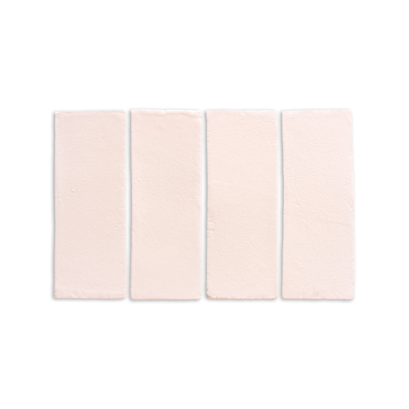 Four pale pinkish-beige matte 2x6 tiles by Clay Imports, with an irregular, handmade surface, laid horizontally.