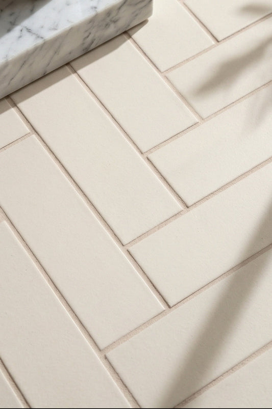 Mexican Vanilla 2.75x8 solid tile by Clay Imports, with a textured creamy surface in a herringbone pattern, with a marble tray and soft shadows.