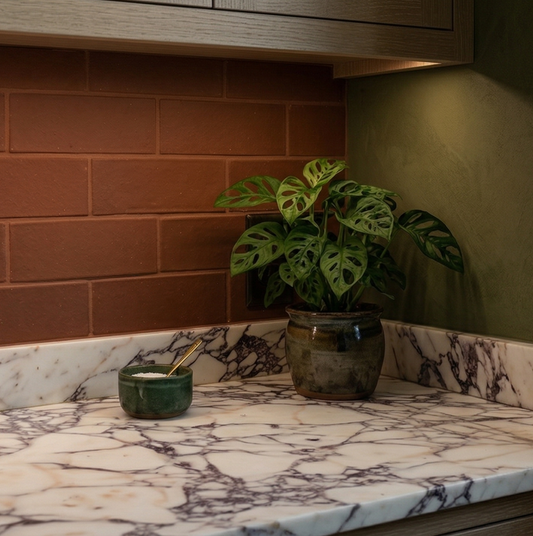 Textured reddish-brown Cotto Tierra 2x6 tiles by Clay Imports as a kitchen backsplash above marble countertops.