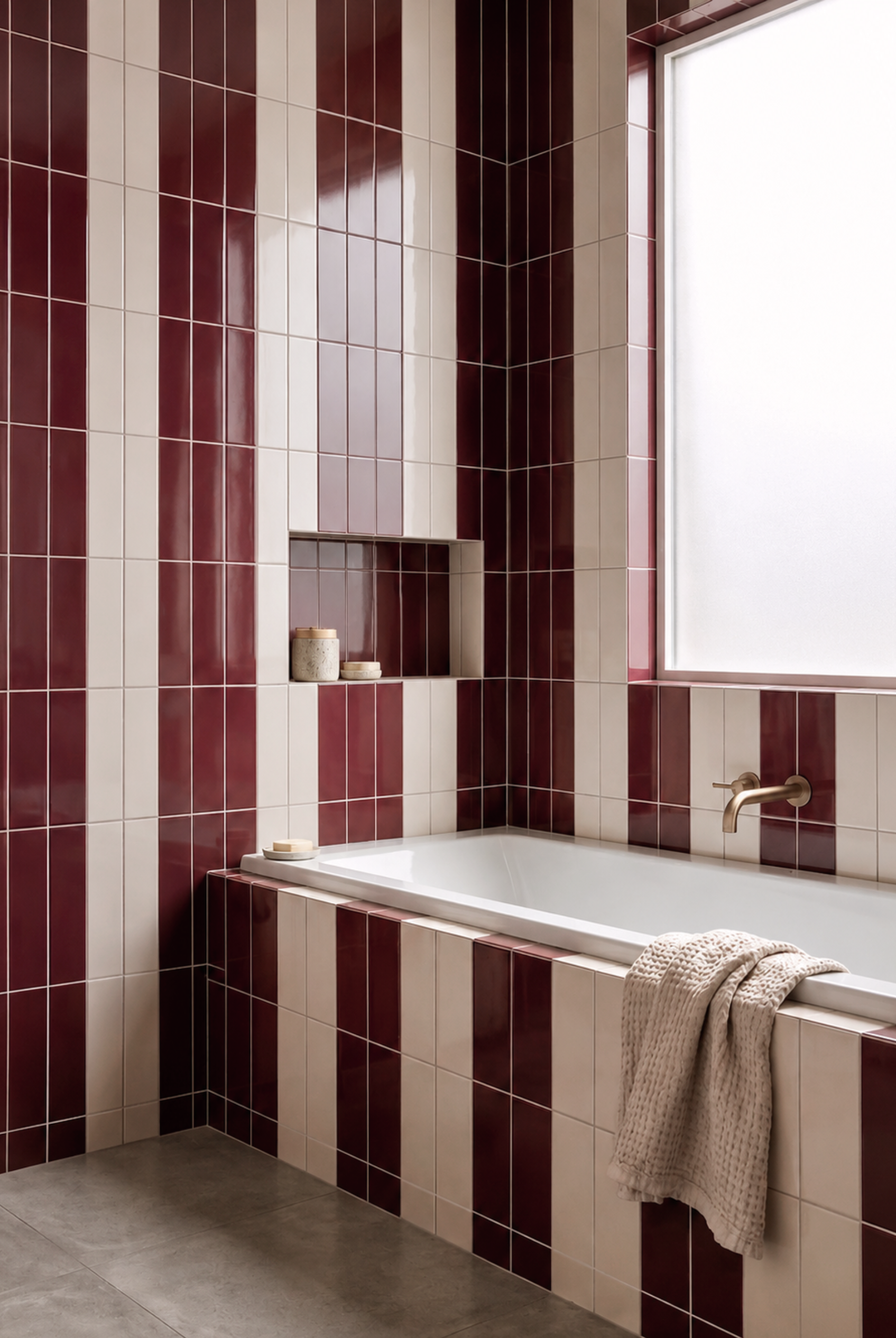 Burgundy glossy 2x8 solid tile by Clay Imports, installed vertically in a striped bathroom wall design with cream tiles.