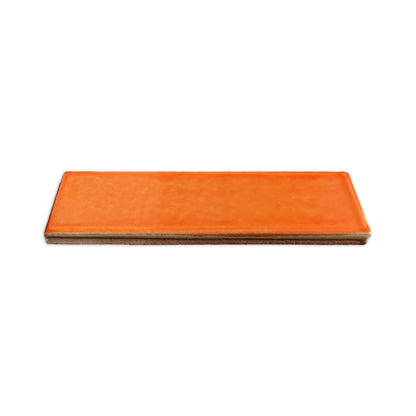 Orange rectangular clay tile by Clay Imports with a textured glazed finish and unglazed base, viewed from the side.