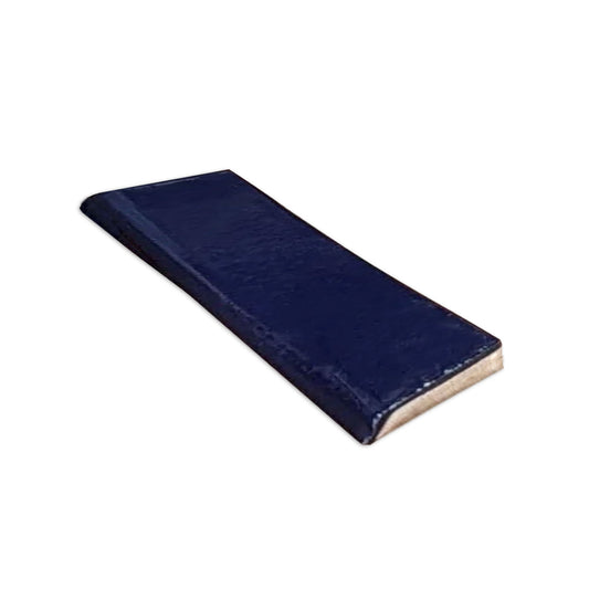 Dark blue gloss 2x8 single bullnose tile by Clay Imports, angled to show its textured surface.