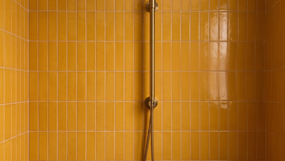 Marigold yellow clay tiles by Clay Imports, vertically stacked in a shower with a brass fixture.