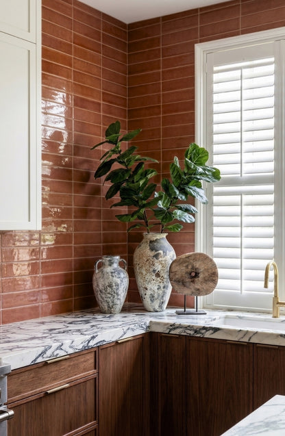 Glossy reddish-brown 2x8 solid tile by Clay Imports, laid in a subway pattern as a kitchen backsplash.