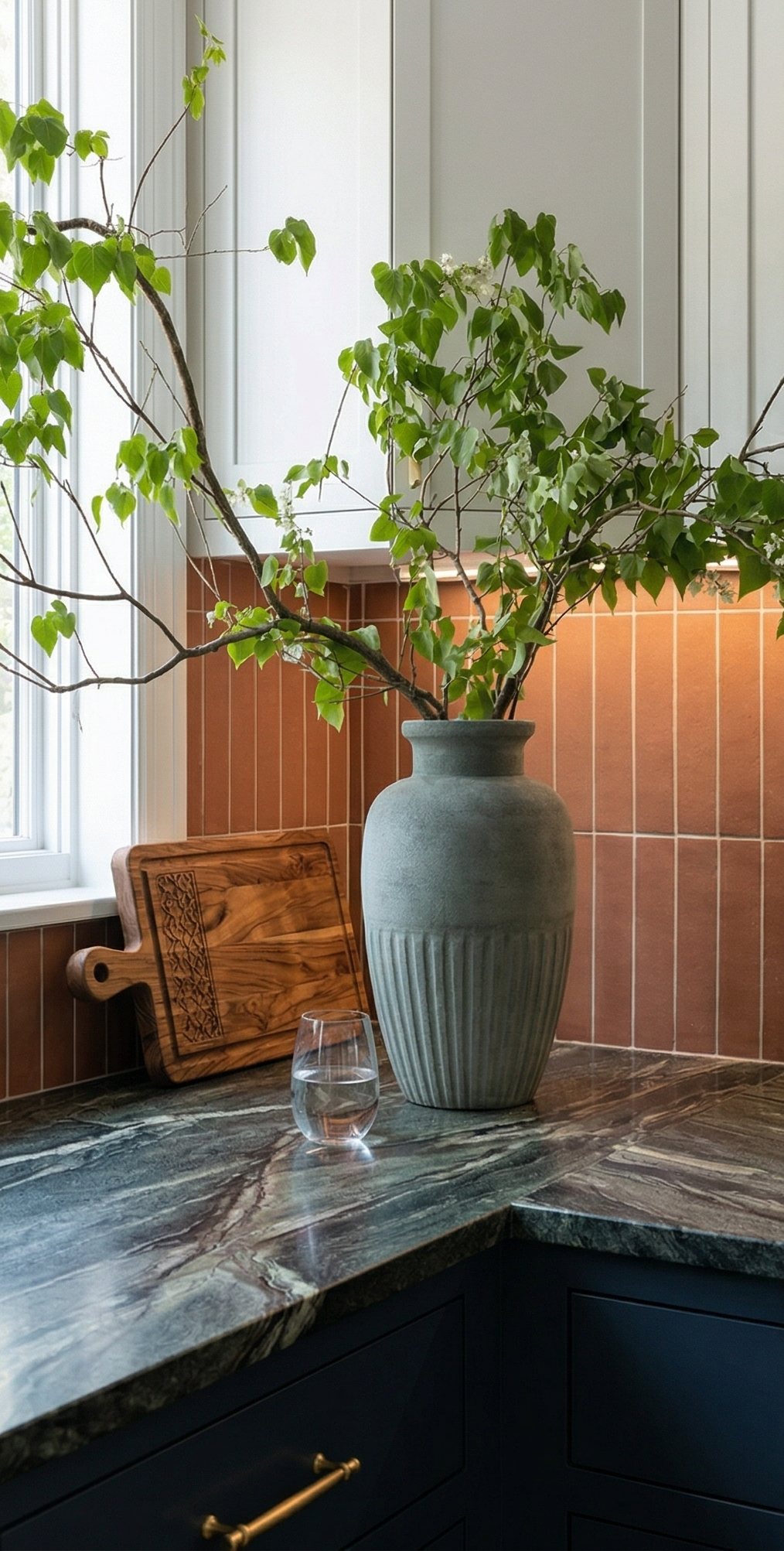 Umber Cotto tile by Clay Imports, vertically arranged as a kitchen backsplash above dark marble and navy cabinets.