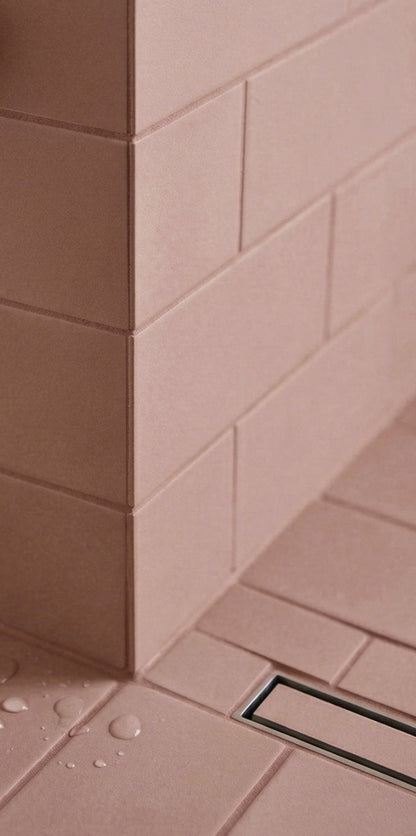 Rosewater Matte Solid Tile by Clay Imports installed in a shower corner, showing its textured surface, a linear drain, and water droplets.