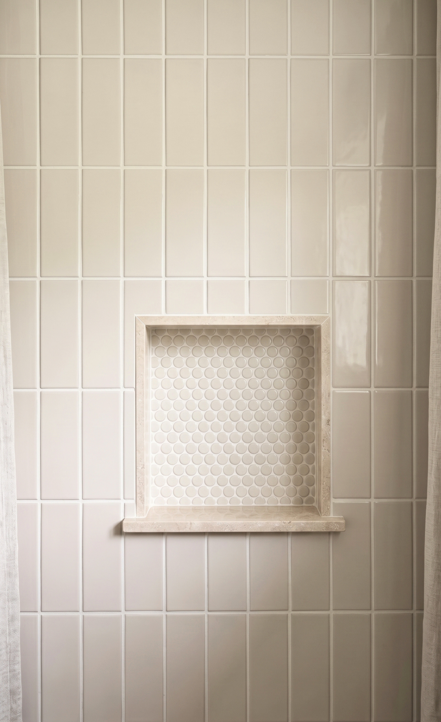 Beige ceramic wall tiles with a recessed niche featuring a white honeycomb patterned tile insert.