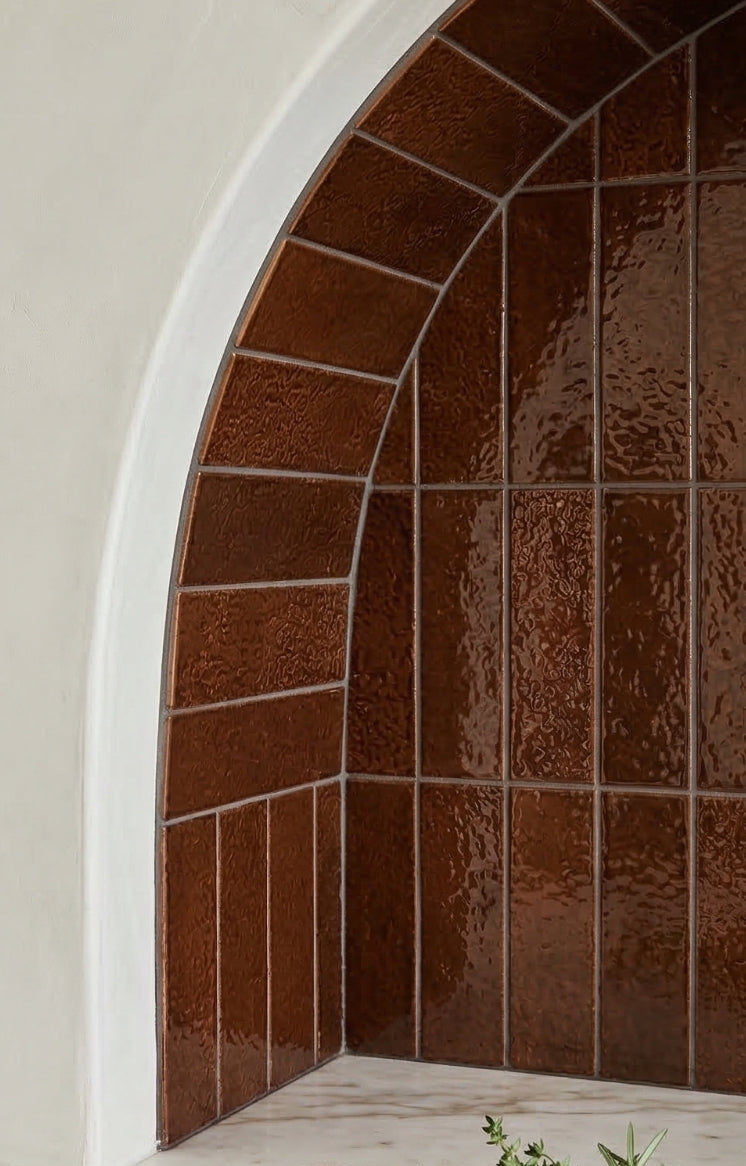 Root Beer Glazed Thin Brick by Clay Imports with an uneven, glossy texture installed in an arched alcove.