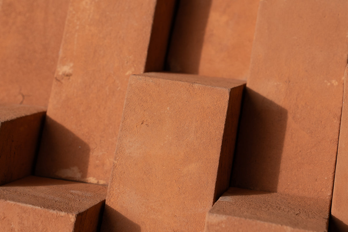 Close-up of stacked terracotta clay blocks with a warm reddish-brown color and visible texture.
