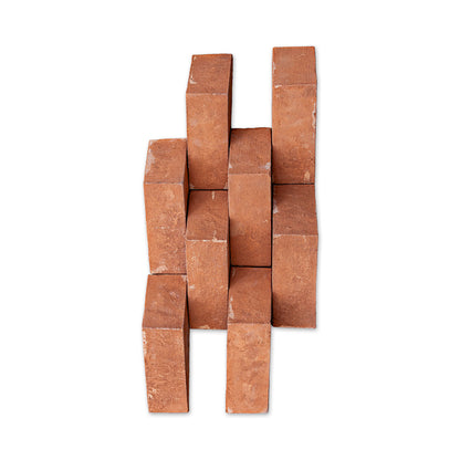 A stack of terracotta clay brick blocks arranged in a staggered, interlocking pattern against a plain white background.