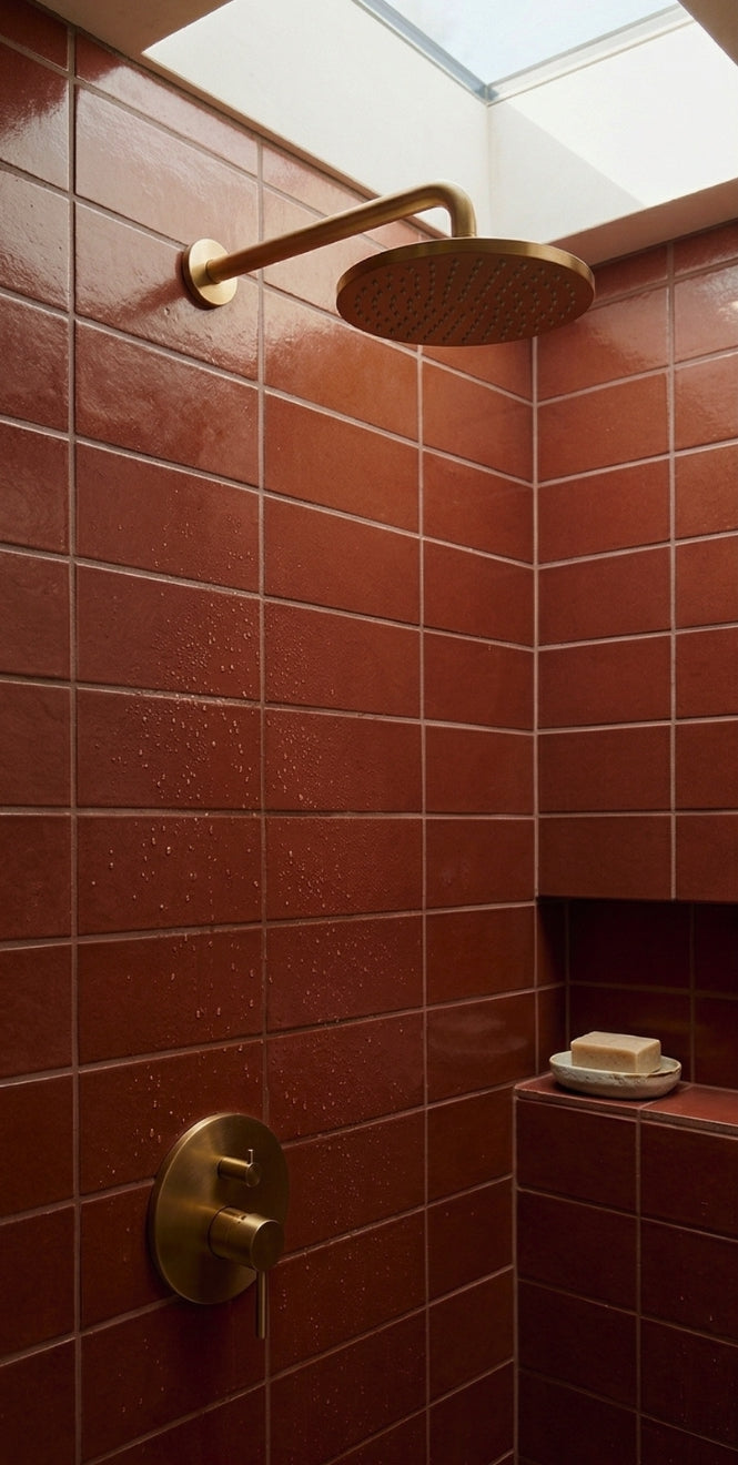 Terracotta-colored Americano 2.75x8 Solid Tile by Clay Imports, installed in a shower with brass fixtures.