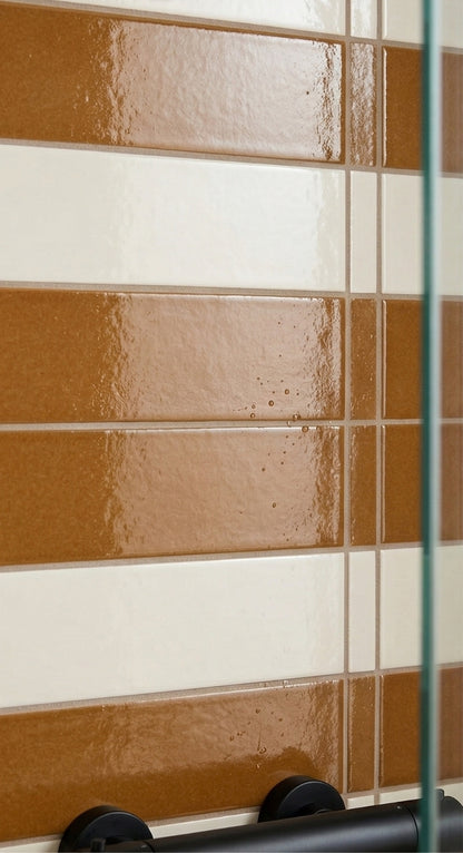 Cajeta brown and cream solid tiles by Clay Imports, showing a glossy finish in a mixed striped pattern with water droplets.