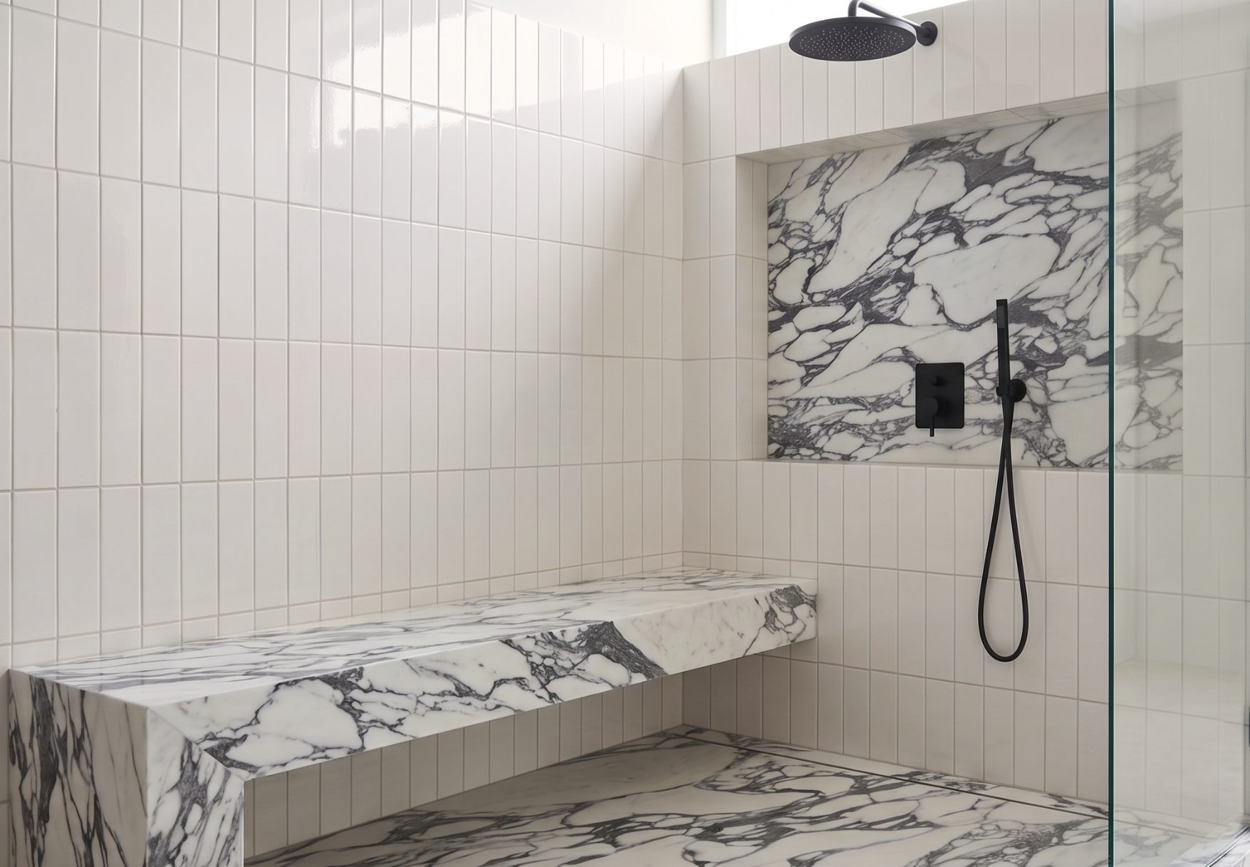 White 3x12 solid tile by Clay Imports in a vertical subway pattern, glossy, lining a modern shower with marble and black fixtures.