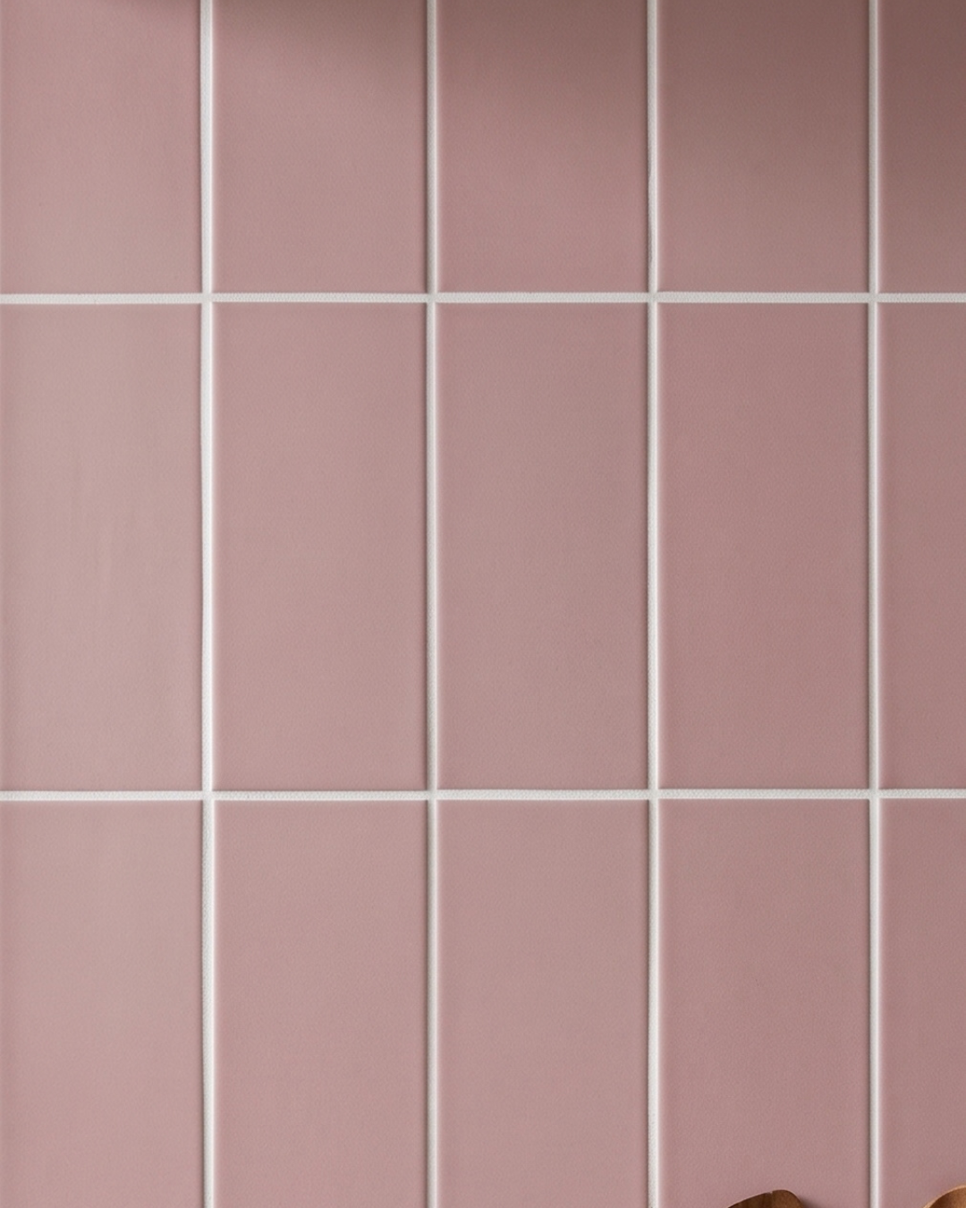 Glossy pink rectangular tiles with white grout create a clean, modern wall backsplash.