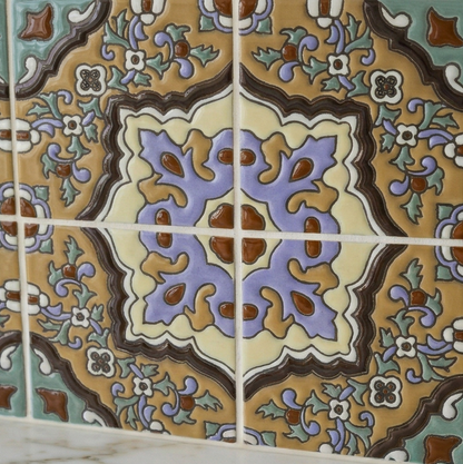 Relief Talavera tile by Clay Imports, with an intricate floral and geometric pattern in brown, gold, purple, and green.