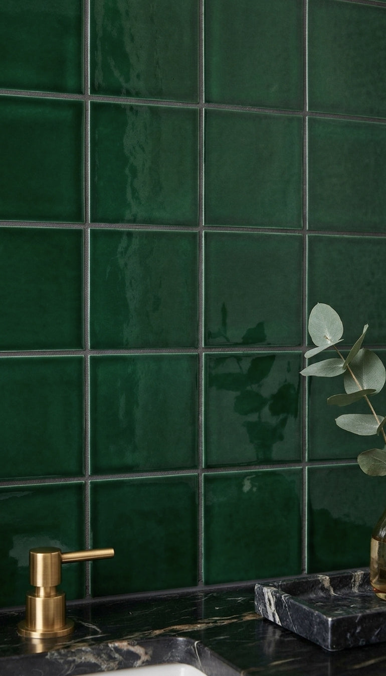 Emerald 4.25x4.25 solid tile by Clay Imports, glossy dark green with texture variations on a bathroom wall.