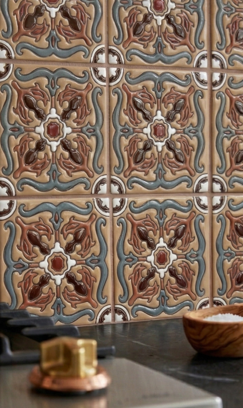 Beige Relief Talavera tile by Clay Imports, featuring an ornate embossed pattern in shades of brown, red, and blue.