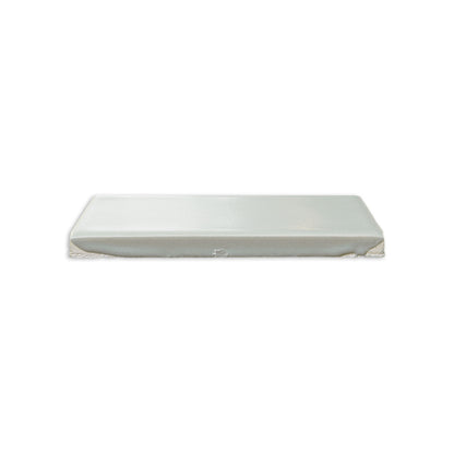 Matte white rectangular tile by Clay Imports, shown in a side view with a smooth surface and rough bottom edge.