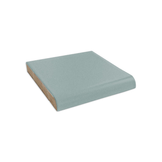 A light blue matte single bullnose tile by Clay Imports, viewed from the side, revealing its rounded edge and unglazed base.