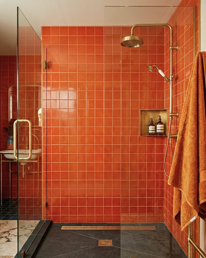 Brandy 4.25x4.25 inch square orange clay tiles by Clay Imports in a modern bathroom with bronze fixtures.