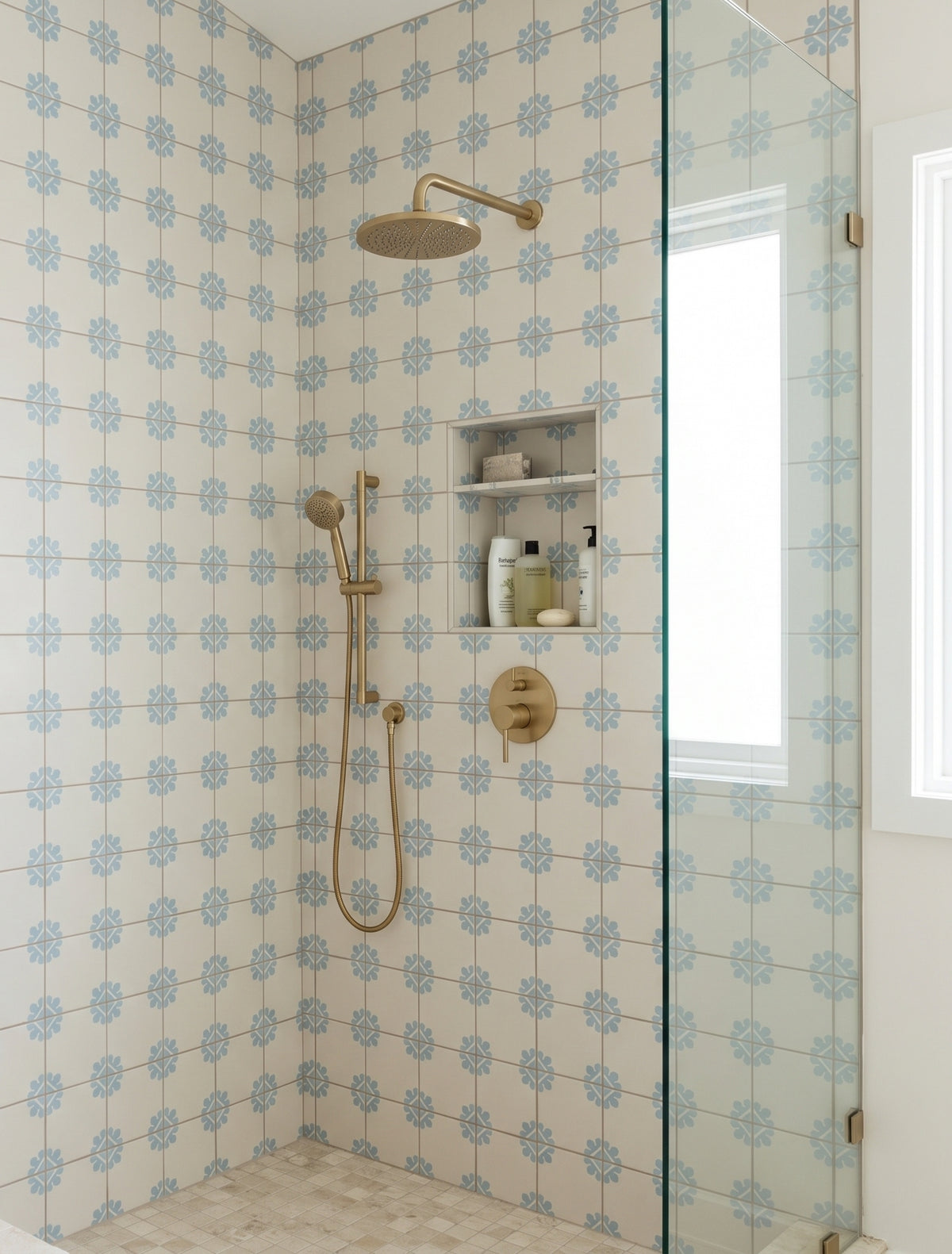 Cream and blue floral patterned Talavera tile by Clay Imports in shower, with gold fixtures and glass enclosure, lifestyle view