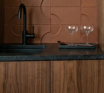 Mamey-colored clay tiles by Clay Imports featuring a raised circular pattern as a kitchen backsplash.