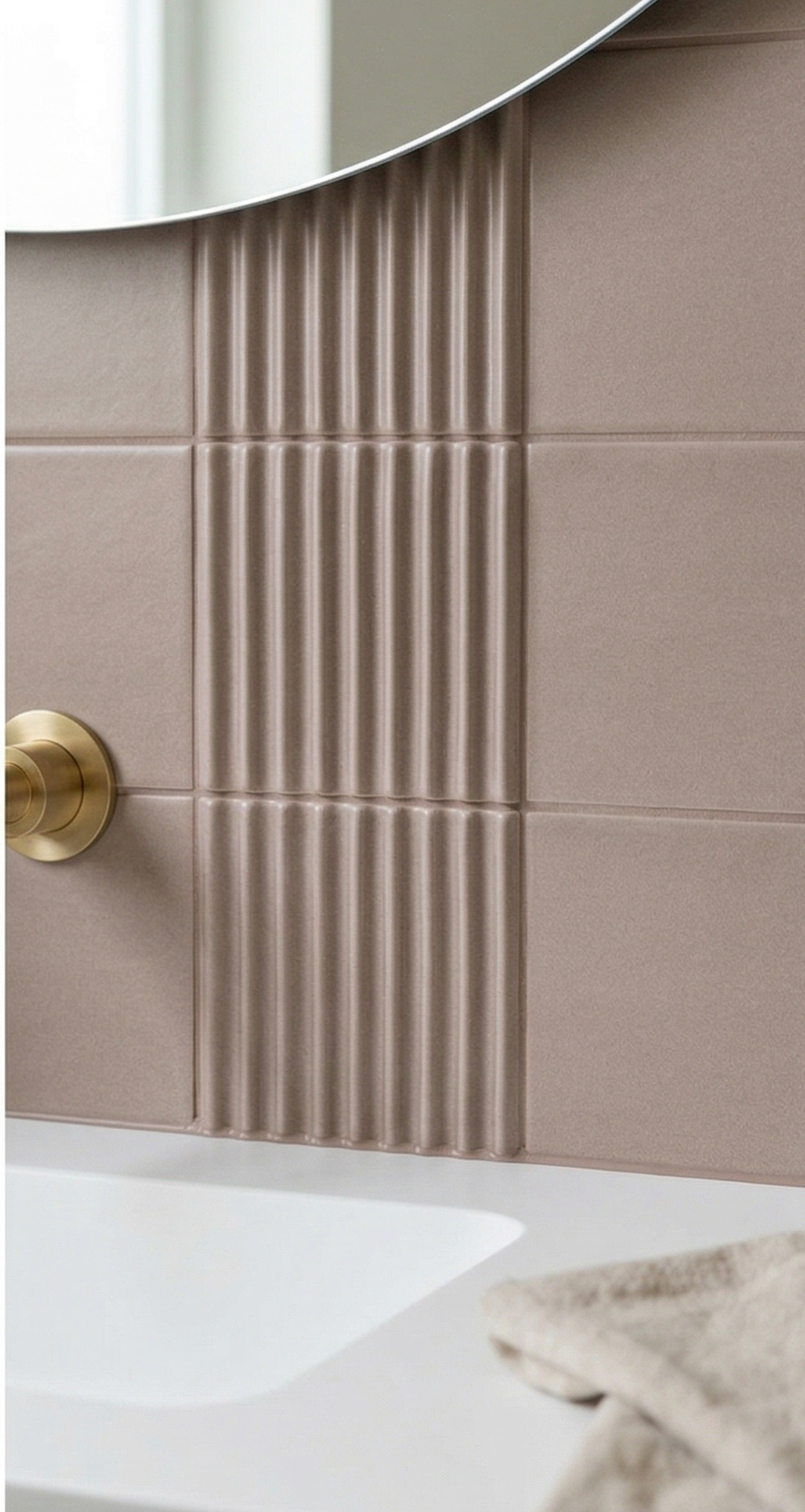 Brown 4x8 clay tiles by Clay Imports with contrasting smooth and vertically fluted textures, installed behind a brass faucet, white sink, and mirror.
