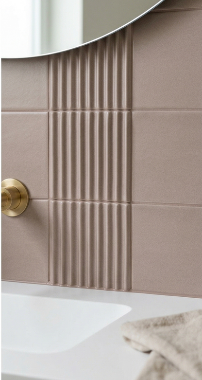 Brown 4x8 clay tiles by Clay Imports with contrasting smooth and vertically fluted textures, installed behind a brass faucet, white sink, and mirror.