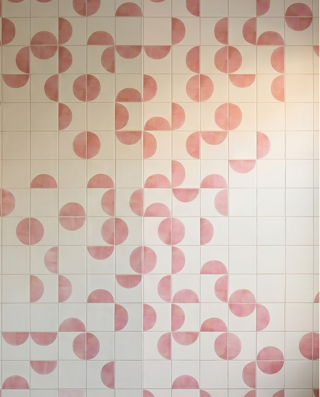 Shower area with pink and white geometric patterned tiles.


