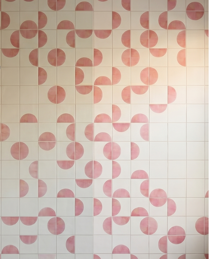 Shower area with pink and white geometric patterned tiles.

