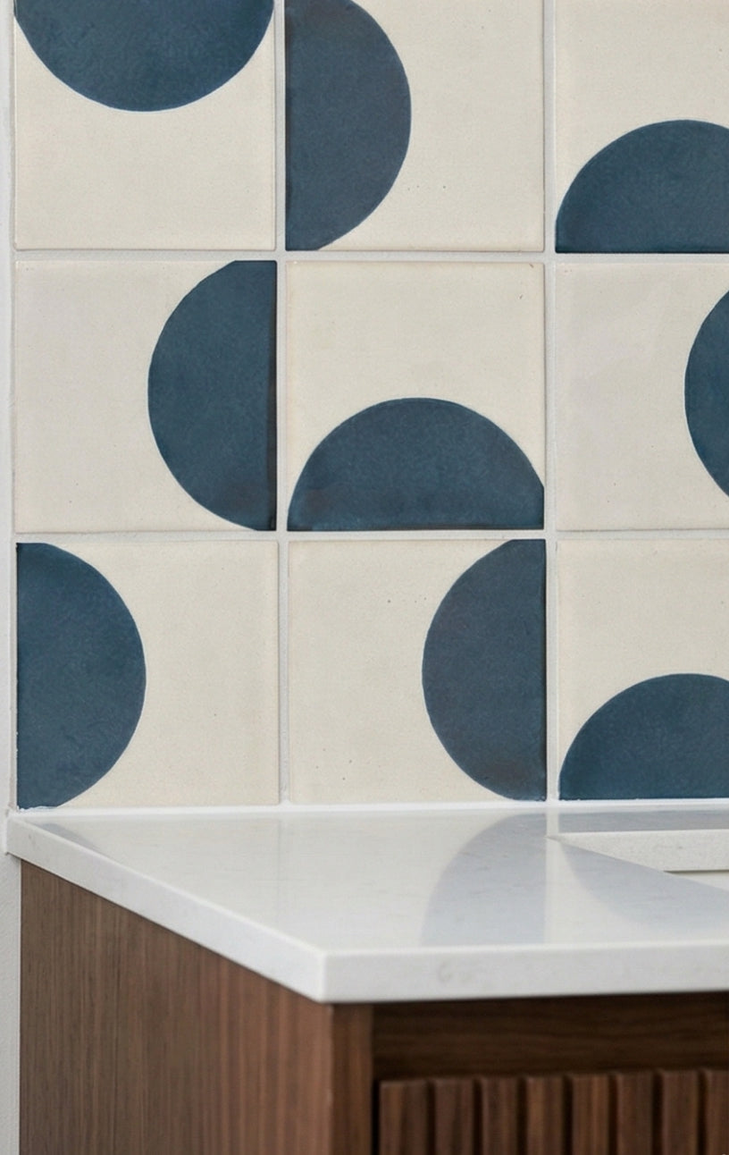 Off-white solid tile with dark blue half-circle pattern by Clay Imports, forming a geometric backsplash.