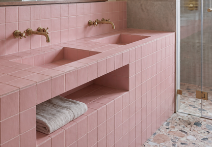 Pink tiled bathroom with a sink and towel