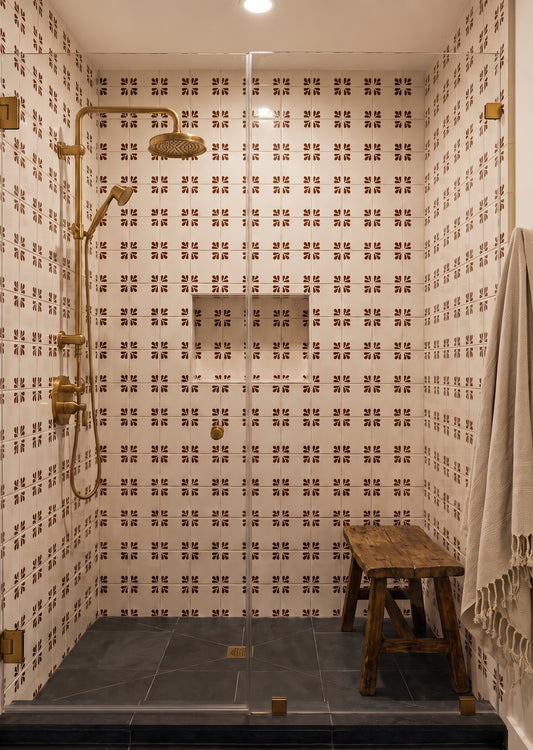 Oxblood Talavera tile by Clay Imports Handmade Tile featuring a Tula pattern on a white background, installed in a shower with brass fixtures.