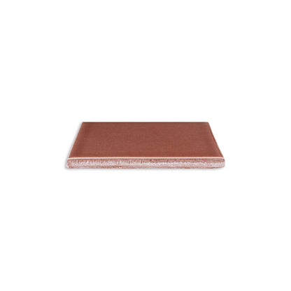 Tamarindo Gloss 4x5 solid tile by Clay Imports, reddish-brown with a glossy top and rough light underside, viewed from the side.