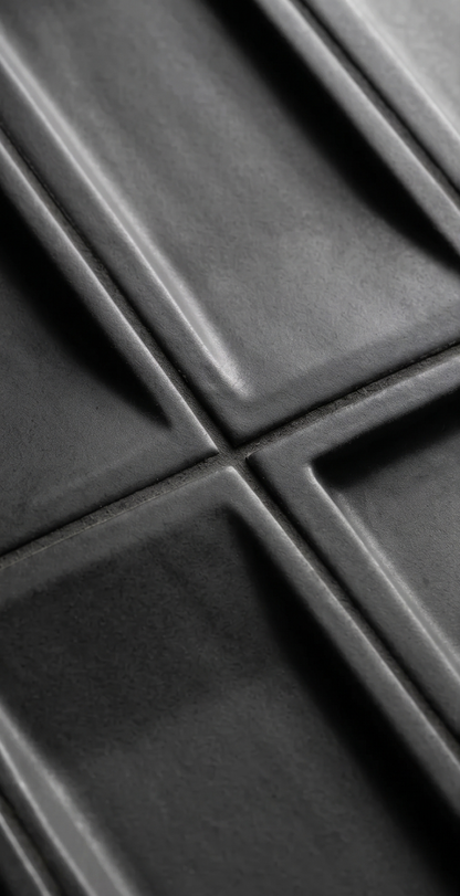 Dark matte black geometric relief tile by Clay Imports, showing raised square patterns and visible grout lines.