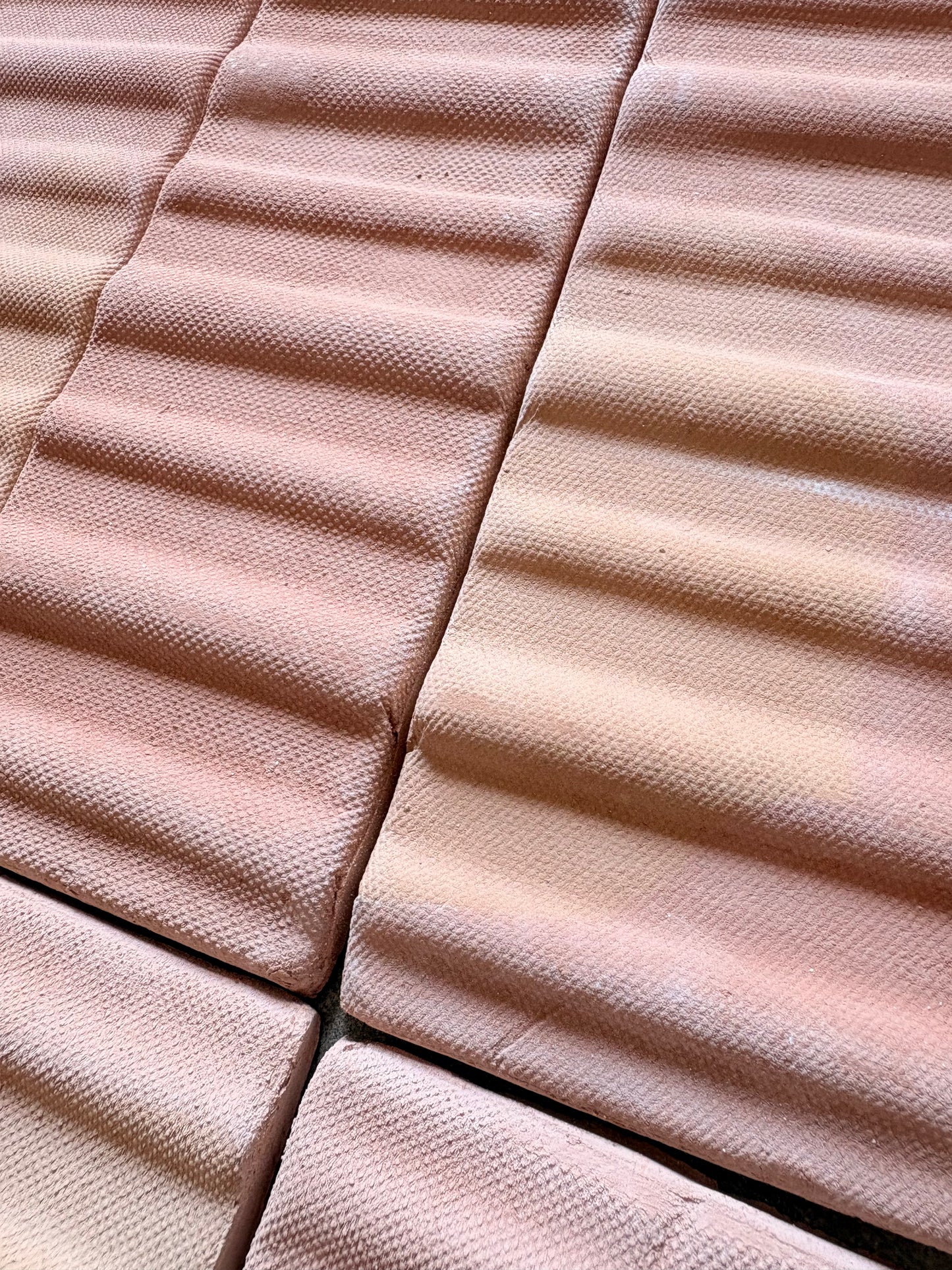 Terracotta matte sealed 3D hatch tiles by Clay Imports, arranged in a bundle with wavy, granular textures.