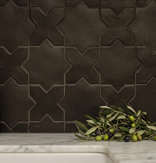 Black suede tile with Star & Cross pattern by Clay Imports, installed as a backsplash over a white marble counter with olive branches.